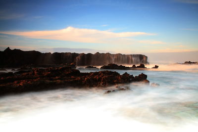 Scenic view of rocks in sea against sky during sunset