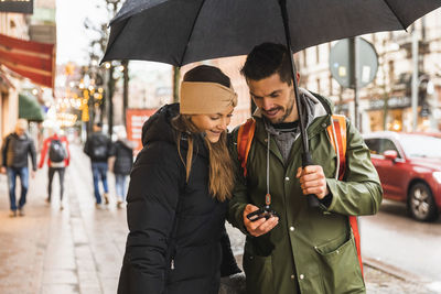 Friends standing on street in rain