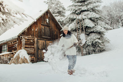 Smiling young woman playing with snow