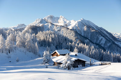 Picturesque winter scene with traditional alpine chalet and snowy forest. austria, alps