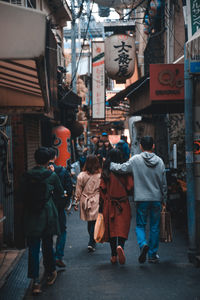 Rear view of people walking on street in city