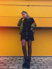 Portrait of young woman standing on footpath