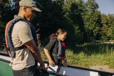 Counselor and girl carrying kayak at summer camp