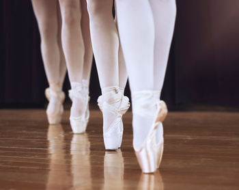 Low section of ballet dancer dancing on hardwood floor