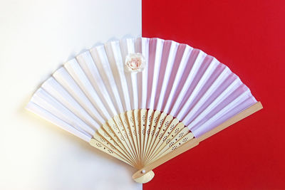 High angle view of hand fan on colored background