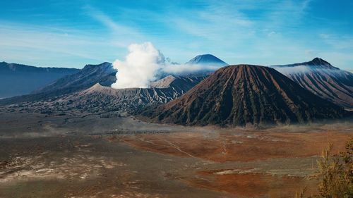 Smoke emitting from volcanic mountain against sky