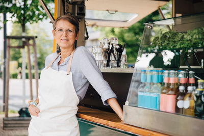 Portrait of mature woman standing by commercial land vehicle