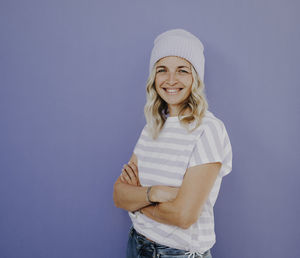 Portrait of young woman standing against wall