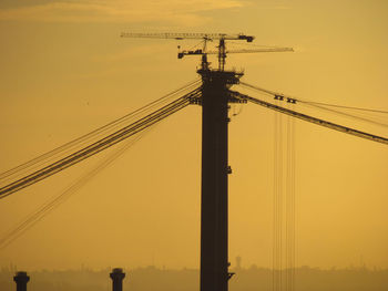Low angle view of crane against sky during sunset
