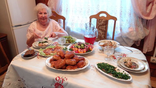 Portrait of a smiling young woman with food on table