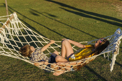 High angle view of siblings relaxing in hammock