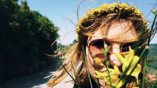 Close-up portrait of woman in sunglasses by flowers