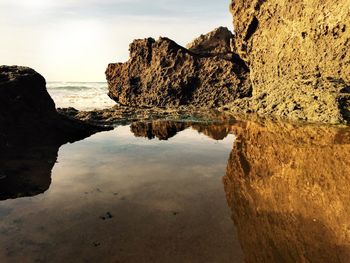 Rock formations by sea against sky