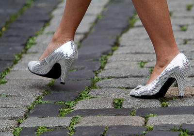 Woman in silver high heels walks over cobblestone street