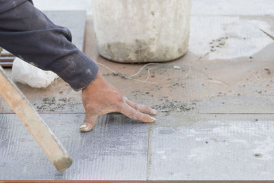 Cropped hand of man laying tiles on floor