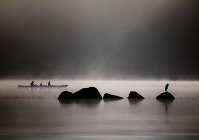Silhouette people on lake against sky