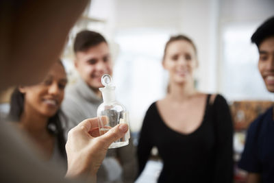 Cropped image of mature female teacher holding solution in glassware while explaining to young multi-ethnic students in