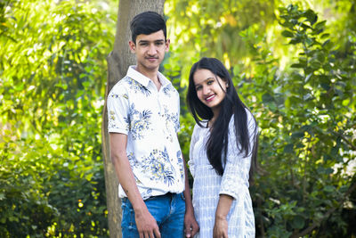 Portrait of young couple standing against plants