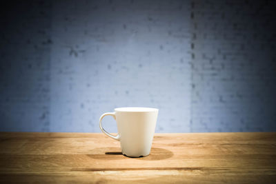 Close-up of coffee cup on table against wall