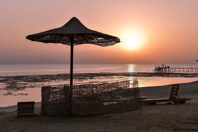 Traditional windmill on beach against sky during sunset