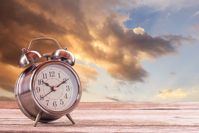 Close-up of clock on table at sunset