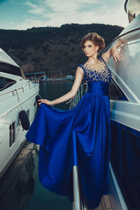 Portrait of smiling young woman standing on car