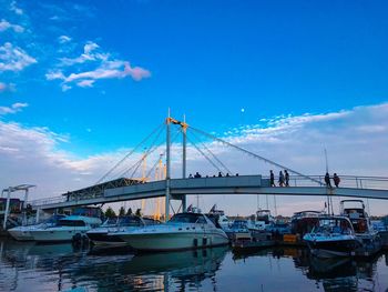 Boats moored at harbor against blue sky