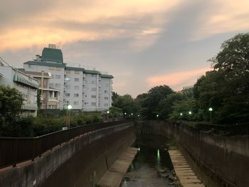 Canal amidst buildings against sky at sunset