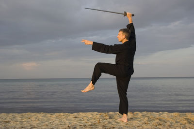 Man practicing tai chi on sand at beach