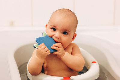 Sweet funny baby taking a bath. baby chewing a toy in a bath chair.