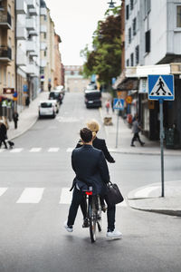 Rear view of man riding bicycle on city street