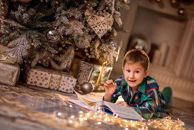 Portrait of happy boy with christmas tree on floor