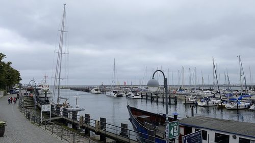 Boats moored at harbor against sky