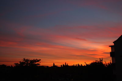Silhouette trees and buildings against sky during sunset