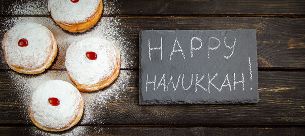 Happy hanukkah. traditional dessert sufganiyot on dark wooden background. donuts, candles and gifts