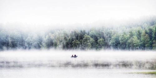 Boats in river with trees in background