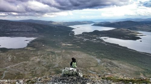 Rear view of man standing on mountain against sky