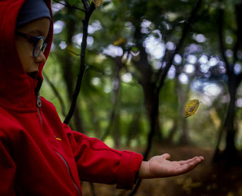 Side view of boy wearing warm clothing catching leaf in park