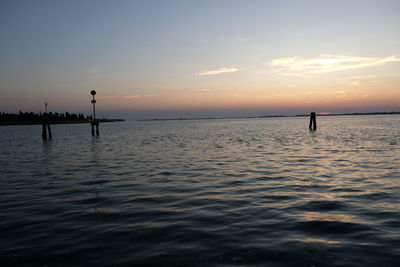 Silhouette people on sea against sky during sunset