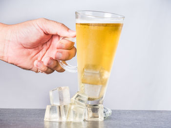 Hand holding glass of beer on table