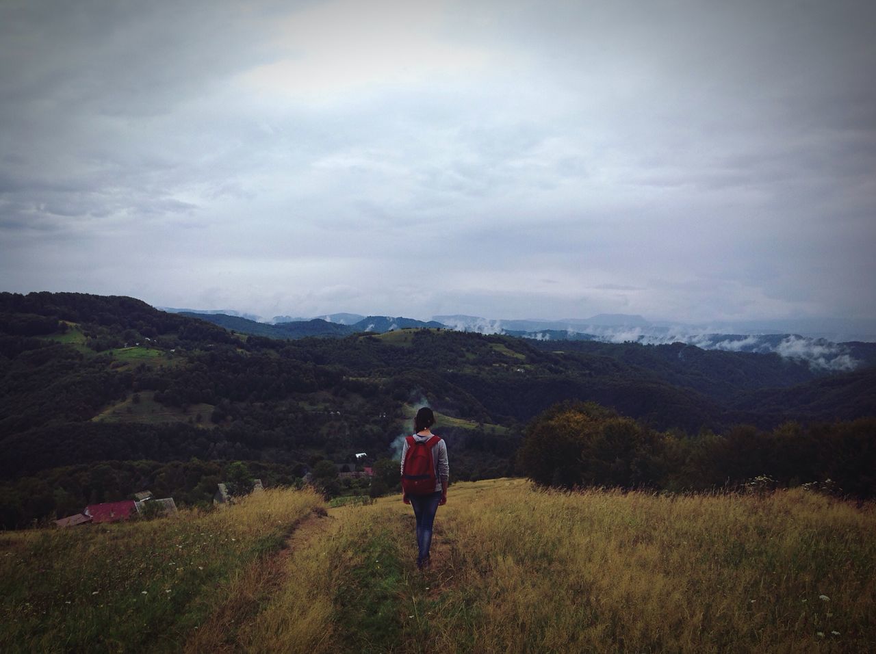 rear view, leisure activity, mountain, lifestyles, men, full length, standing, cloud - sky, sky, mountain range, grass, landscape, scenics, tranquil scene, tranquility, casual clothing, field, beauty in nature, nature, cloudy, remote, tourist, day, growth, vacations, non-urban scene, solitude, outdoors, cliff, getting away from it all, tourism