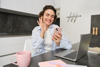 Businesswoman using mobile phone while sitting on table