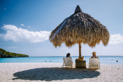 People relaxing on beach against sky