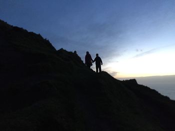 Low angle view of silhouette people on mountain against sky