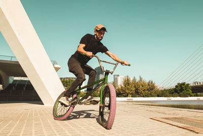 Man riding bmx cycle on footpath in city