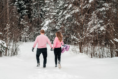 Rear view of women walking on snow covered land