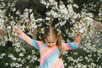 Portrait of smiling young woman standing amidst flowers