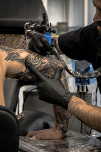 Artist making tattoo on shirtless man shoulder