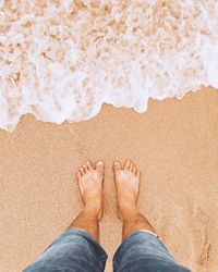 Low section of man standing on beach