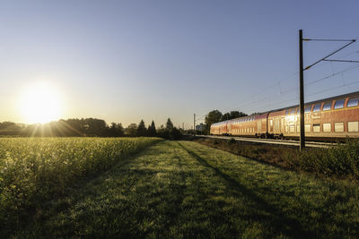 Train on field against clear sky during sunset